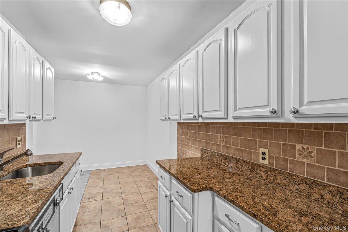 35-30 73rd Street, Unit 1F Queens, NY 11372 - Photo 12 of 24 a kitchen with granite countertop a sink a stove and cabinets