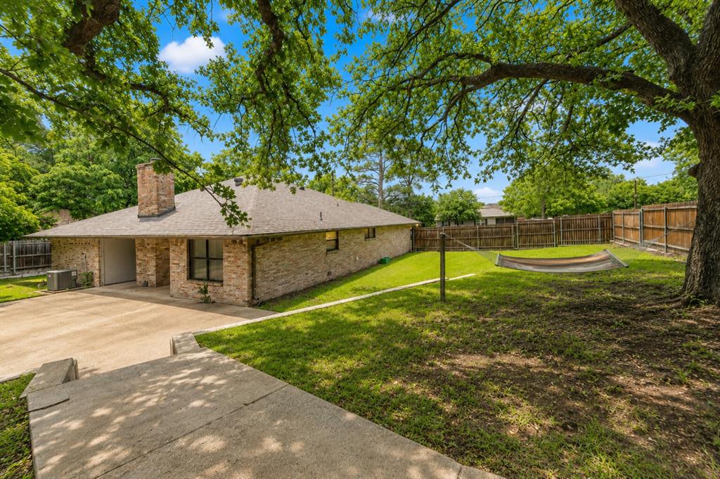 1001 Rosebud Drive Azle, TX 76020 - Photo 34 of 36 Brick exterior featuring a prominent chimney, a multi-car concrete driveway, a single-car garage, and a large front yard with mature trees
