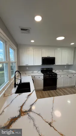 a kitchen with granite countertop a stove sink and cabinets