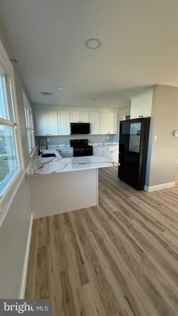 a large kitchen with kitchen island a stove a sink dishwasher and a refrigerator with wooden floor