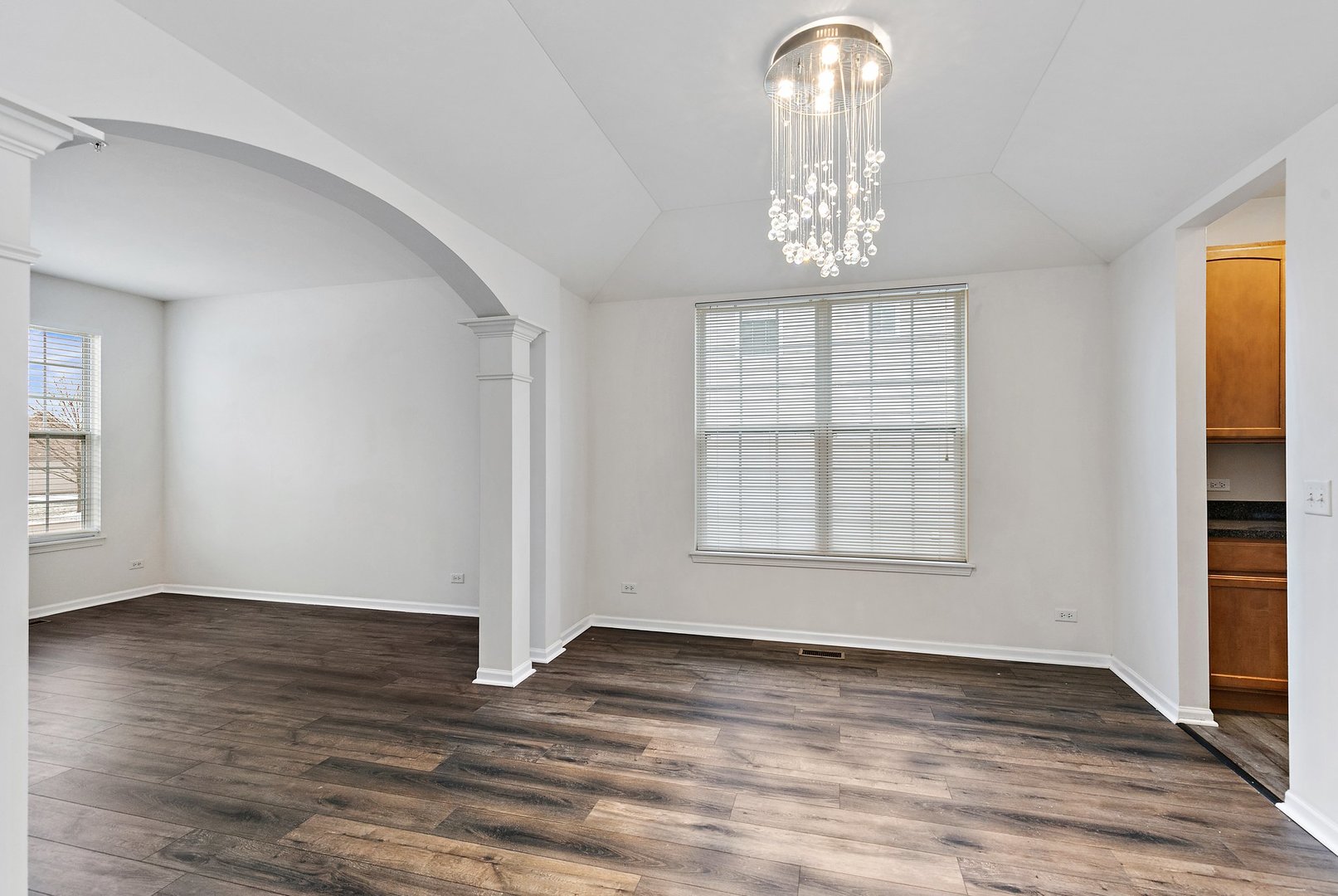 5734 Red Oak Drive Hoffman Estates, IL 60192 - Photo 6 of 31 an empty room with wooden floor chandelier and windows
