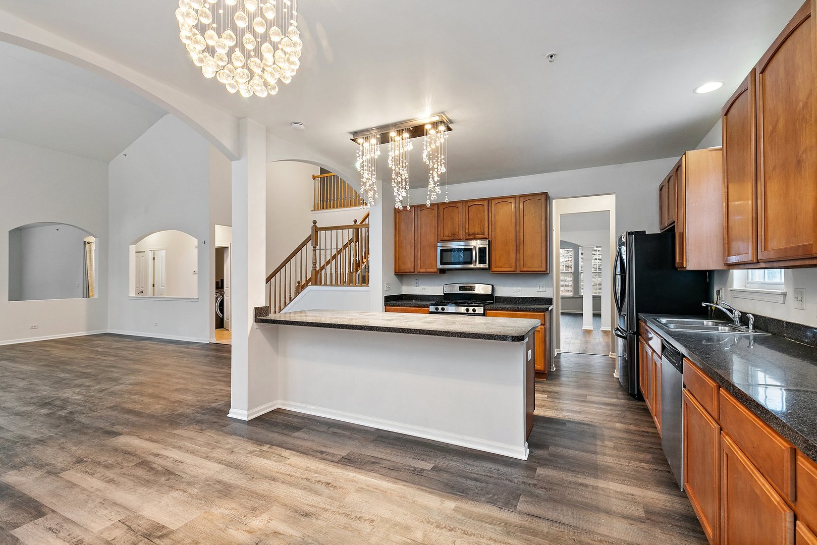 5734 Red Oak Drive Hoffman Estates, IL 60192 - Photo 9 of 31 a large kitchen with kitchen island granite countertop a sink dishwasher a stove and a dining table with wooden floor