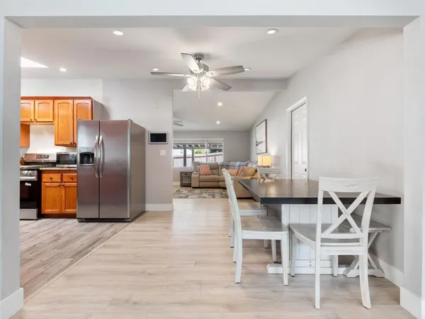 a kitchen with stainless steel appliances kitchen island granite countertop a table chairs and a refrigerator