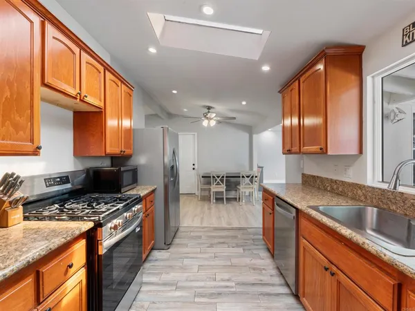 a kitchen with stainless steel appliances kitchen island granite countertop a table chairs and a refrigerator