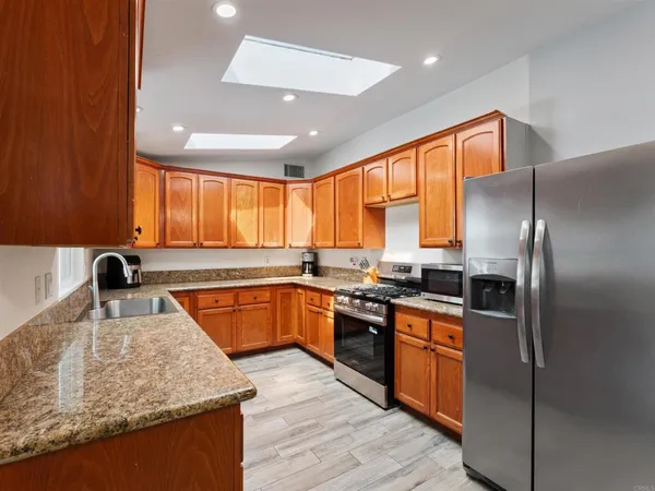 a kitchen with granite countertop wooden cabinets stainless steel appliances a sink and window