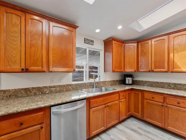 a kitchen with granite countertop wooden cabinets stainless steel appliances a sink and window