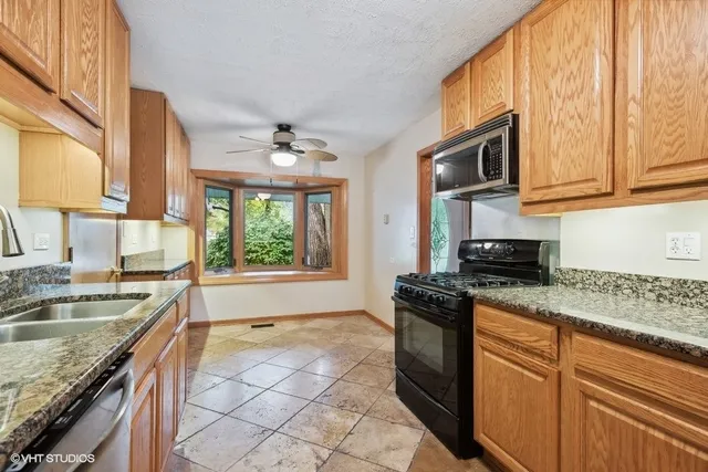 a kitchen with stainless steel appliances granite countertop a sink stove and cabinets