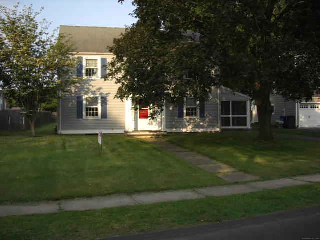 a view of a white house next to a yard with big trees