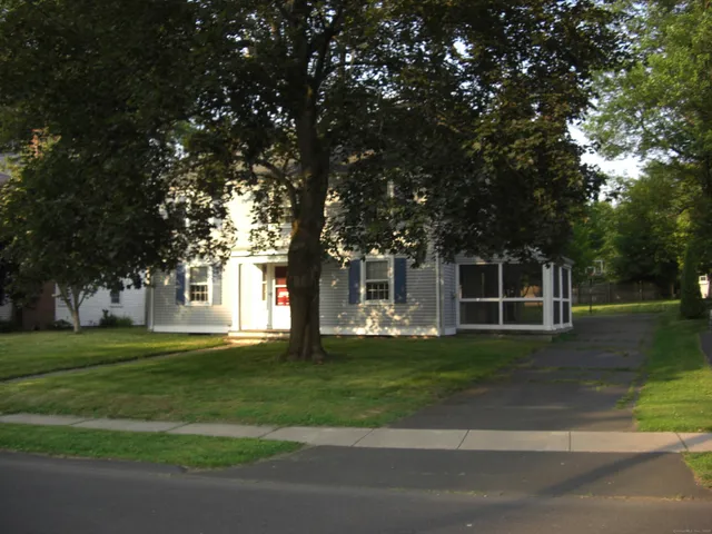 a view of a house with a big yard and large trees