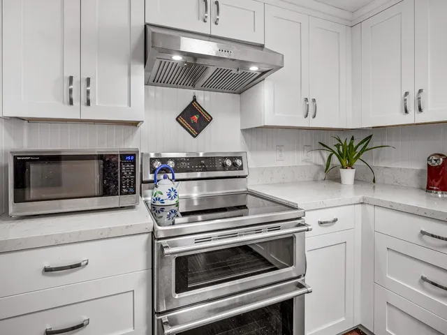 a kitchen with white cabinets stainless steel appliances and wooden floor