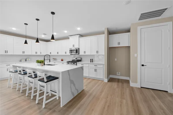 a kitchen with stainless steel appliances kitchen island granite countertop a table chairs sink and cabinets