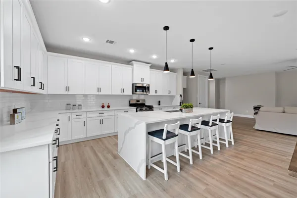 a kitchen with a dining table chairs wooden floor cabinets and stainless steel appliances