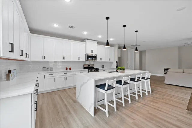 a kitchen with a dining table chairs wooden floor cabinets and stainless steel appliances