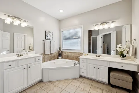 a bathroom with a double vanity sink mirror and bathtub