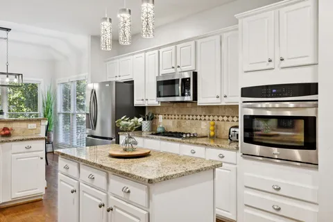a kitchen with granite countertop a sink stainless steel appliances and white cabinets
