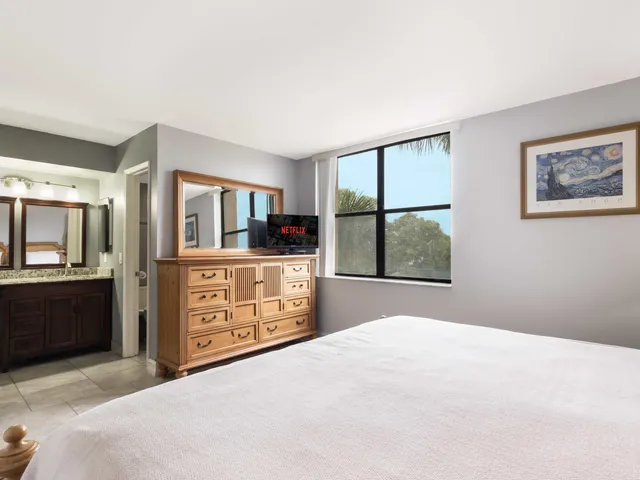 a bedroom with a bed a dresser and painting on the wall