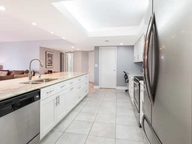 a large white kitchen with a sink and dishwasher a refrigerator a stove top oven with wooden floor