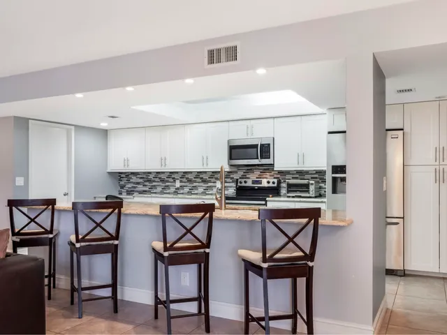 a kitchen with stainless steel appliances kitchen island granite countertop a table chairs microwave and sink