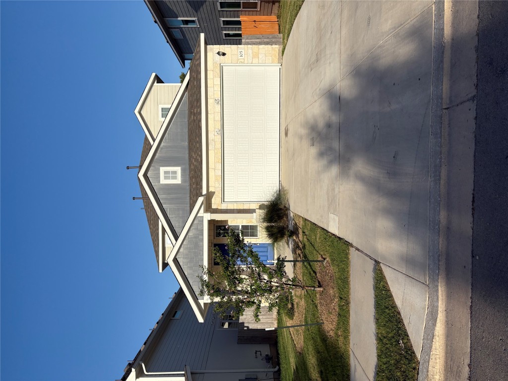View of front of property with driveway, a garage, and a shingled roof