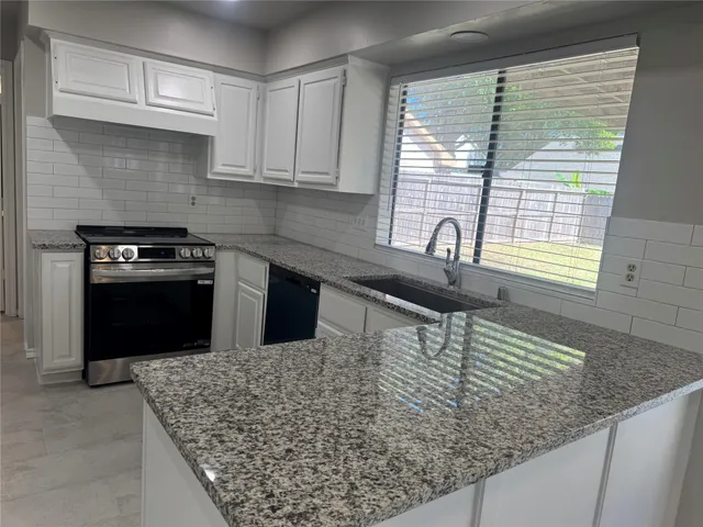 a kitchen with granite countertop a sink a stove and cabinets