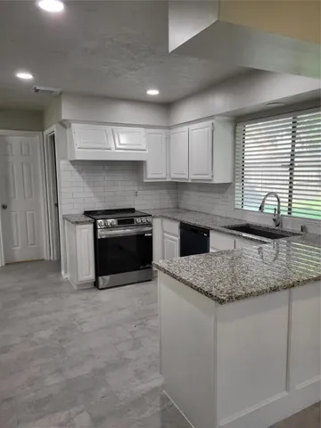 a kitchen with granite countertop a sink a stove and cabinets