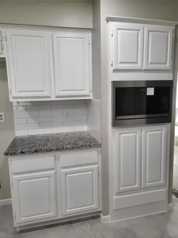 a kitchen with white cabinets and stainless steel appliances