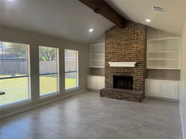 a view of an empty room with a fireplace and a window