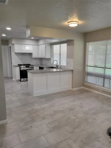 a large white kitchen with kitchen island a sink stainless steel appliances and cabinets