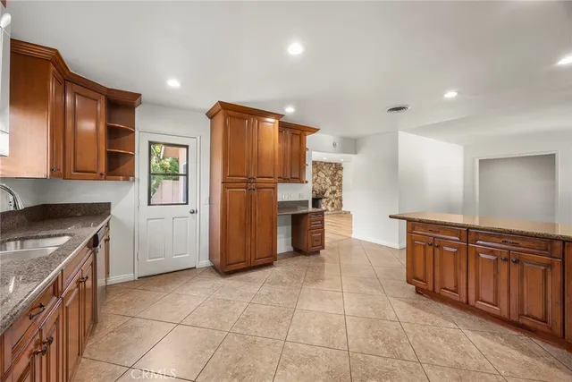 a kitchen with granite countertop a refrigerator and a stove top oven
