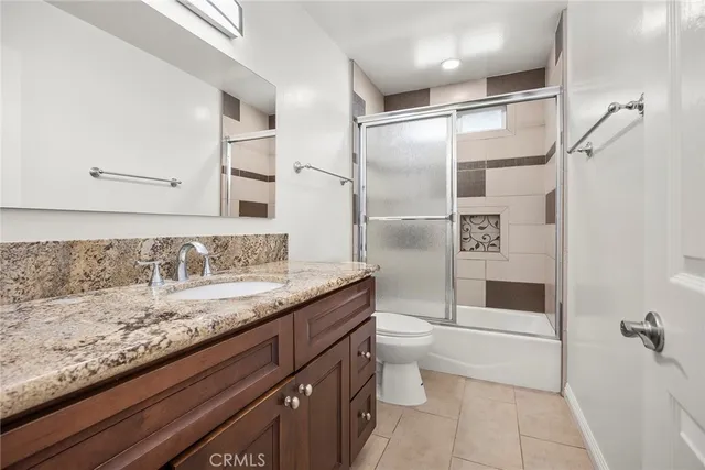 a bathroom with a granite countertop sink a toilet and shower