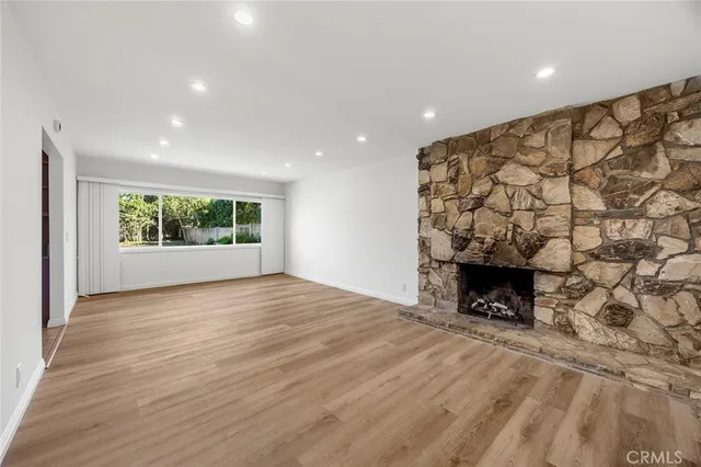 a view of an empty room with a fireplace and window