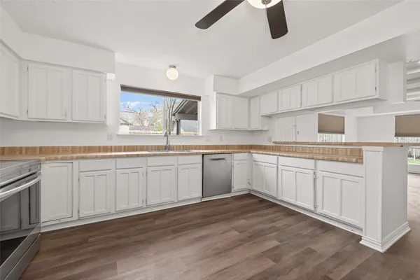 a kitchen with white cabinets stainless steel appliances a sink and a window