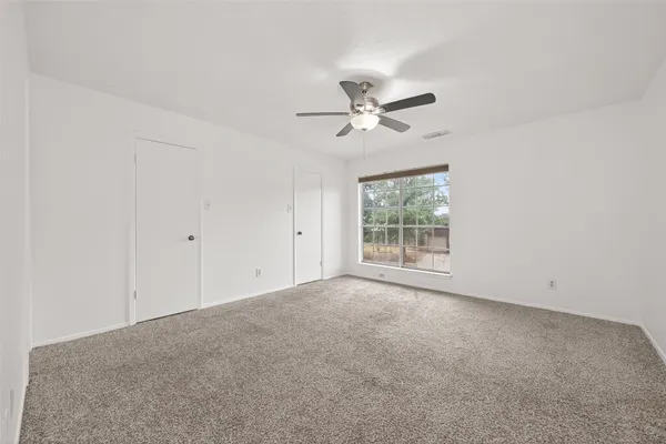 an empty room with a window and a ceiling fan