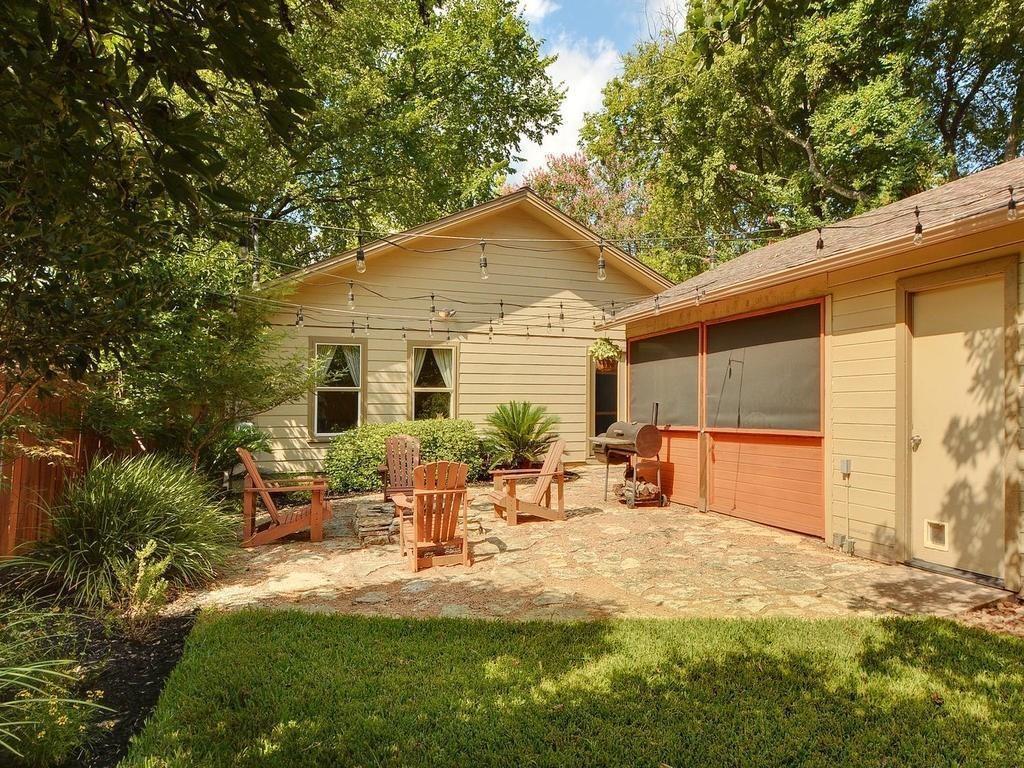 610 West N Loop Boulevard Austin, TX 78751 - Photo 23 of 29 The property features a stone patio area with Adirondack chairs, surrounded by mature trees and string lighting