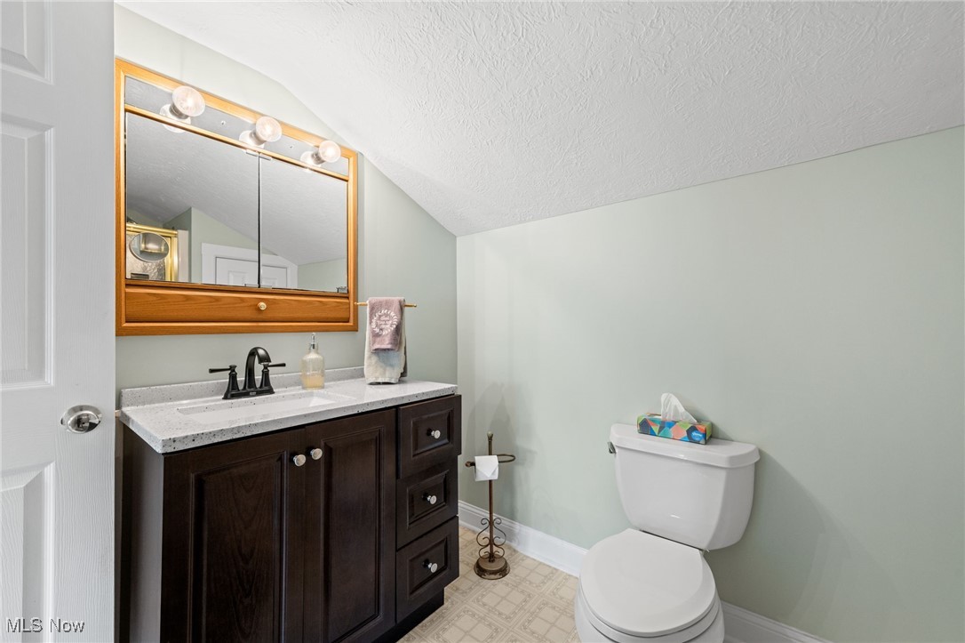 3945 Columbia Road Medina, OH 44256 - Photo 19 of 40 Half bath with vaulted ceiling, a textured ceiling, vanity, and tile patterned floors