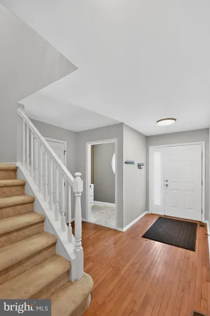 a view of an empty room with wooden floor and stairs