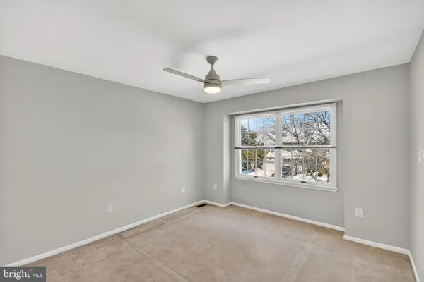 an empty room with windows and ceiling fan