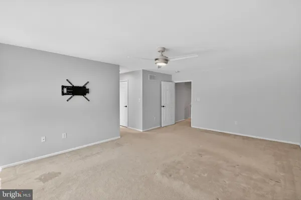 a view of an empty room with a window and kitchen view