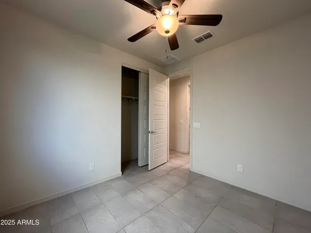 an empty room with closet and a chandelier fan