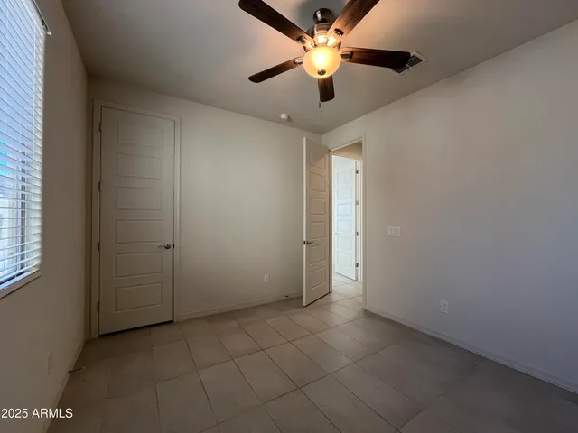 an empty room with closet and a chandelier fan