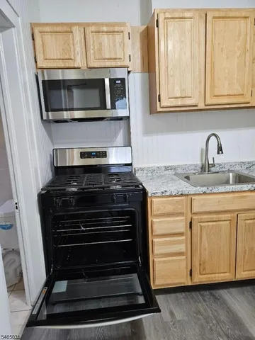 a kitchen with granite countertop cabinets stove microwave and sink