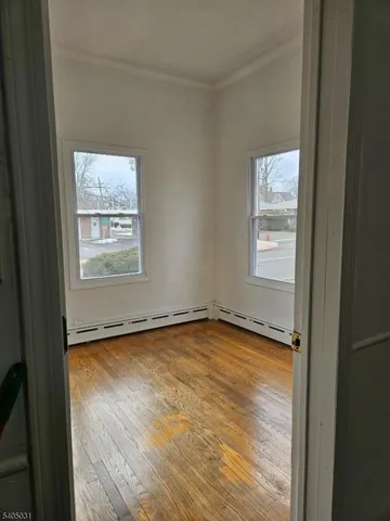 a view of an empty room with a window and wooden floor