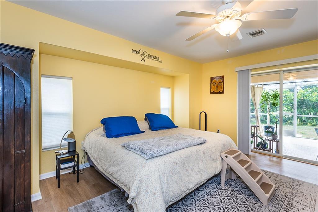 7557 South Blue Sage Punta Gorda, FL 33955 - Photo 25 of 28 a bedroom with a bed a chandelier and a dresser next to a window