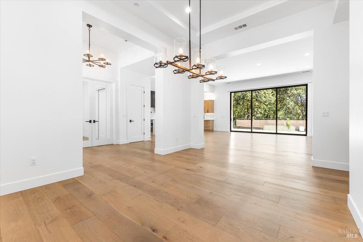 794 Los Olivos Road Santa Rosa, CA 95404 - Photo 18 of 59 an empty room with wooden floor chandelier fan and windows