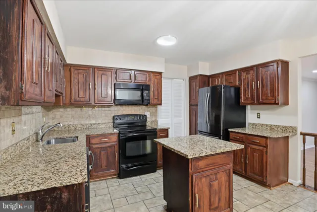 a kitchen with stainless steel appliances granite countertop a stove refrigerator sink and microwave