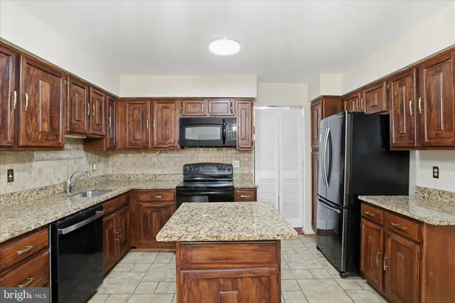 a kitchen with stainless steel appliances granite countertop a stove top oven a refrigerator and a sink