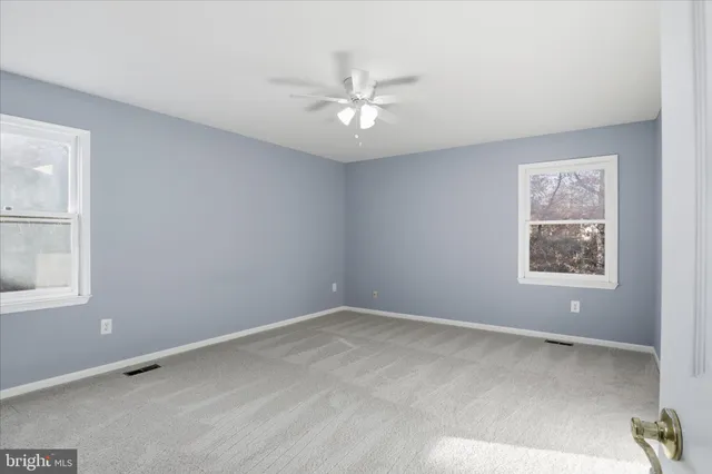 an empty room with a window and ceiling fan