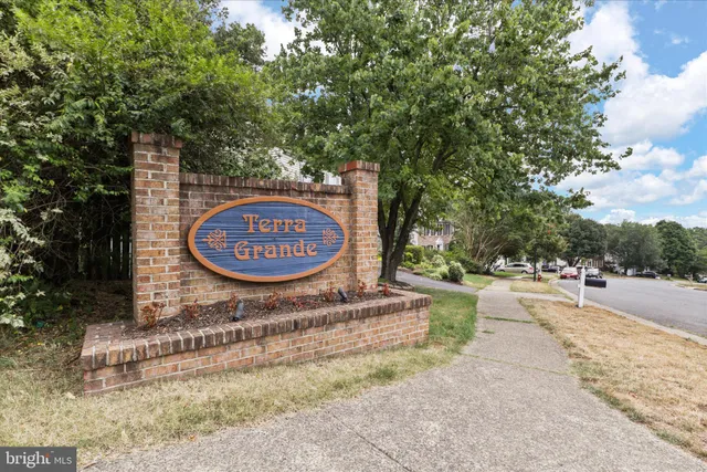 a sign board with a house and yard in the back