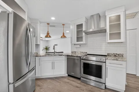 a kitchen with stainless steel appliances granite countertop a stove a refrigerator and a sink