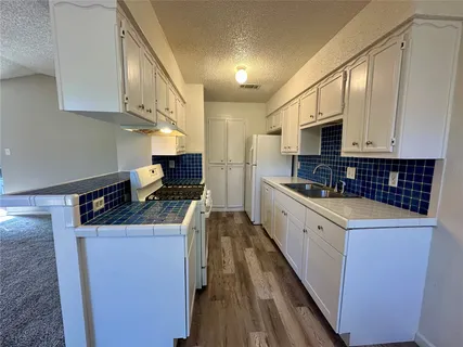a kitchen with granite countertop a stove top oven and cabinets
